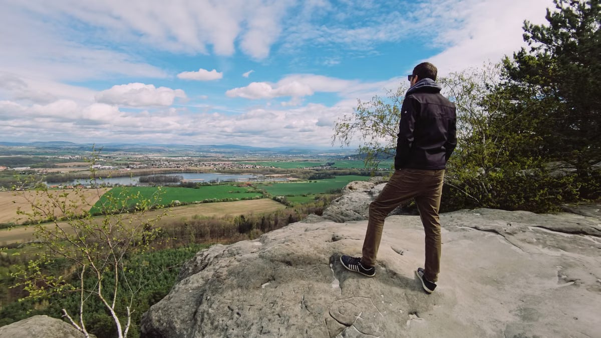 A lone traveler enjoying a scenic overlook under a bright sky.